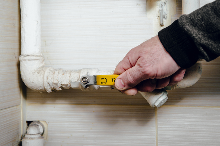 The man touches the yellow valve from the water, gas. The man closes the gas or water supply from the pipeline.